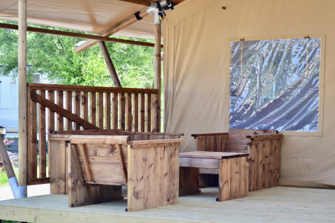 Outdoor seating area with wooden chairs and table in a safari tent at Beach Park “Vlugtenburg 13”, Netherlands.