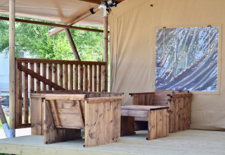 Area salotto all’aperto con sedie e tavolo in legno presso la tenda safari Beach Park «Vlugtenburg 13» nei Paesi Bassi.