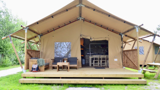 Tienda safari Beach Park Vlugtenburg 13 con terraza de madera, asientos al aire libre y césped.