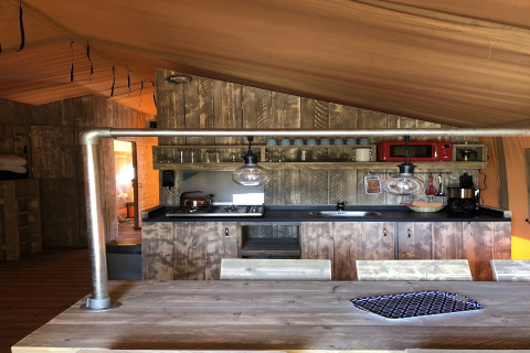 Kitchen area inside a safari tent at Beach Park 'Vlugtenburg 13' in the Netherlands, rustic wood design.