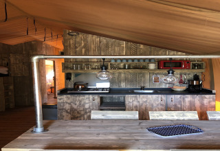 Coin cuisine dans une tente safari au Beach Park 'Vlugtenburg 13' avec meubles en bois rustique et équipements modernes.
