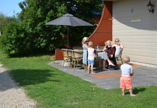 Familia relajándose al aire libre bajo una sombrilla en Beach Park Vlugtenburg 13 en los Países Bajos.