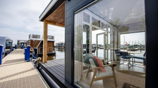 Casa flotante 'Riggelbrug' en Welcome In - Friesland, Países Bajos, con vistas interiores modernas y al puerto.