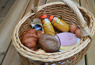 Breakfast basket at Beach Park Vlugtenburg 13 with juice, bread, eggs, and Nescafé, Netherlands.