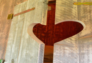 Close-up of a rustic wooden safari tent door with a heart cutout at Beach Park Vlugtenburg 13, Netherlands.