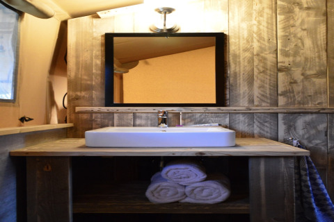 Wood-paneled bathroom in a safari tent at Beach Park Vlugtenburg 13, Netherlands, with sink and towels.