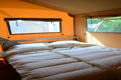 Interior view of a safari tent with a cozy double bed at Beach Park 'Vlugtenburg 12' in the Netherlands.