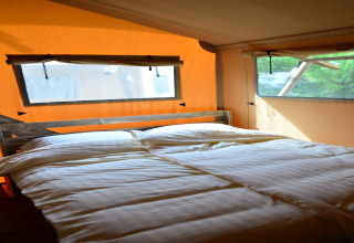 Habitación interior de una tienda safari con cama doble en Beach Park «Vlugtenburg 12», Países Bajos.
