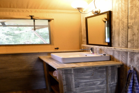 Bathroom inside the safari tent Beach Park 'Vlugtenburg 12' with wooden sink, mirror, and large window view.
