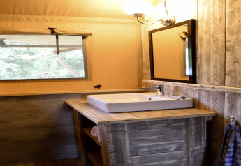 Salle de bain dans la tente safari Beach Park 'Vlugtenburg 12' avec lavabo, miroir et décor en bois.