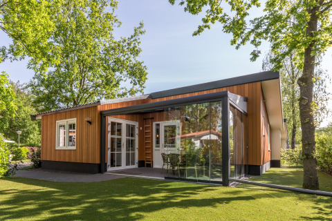 Moderne lodge bij Residence De Eese 3 met houten gevel, glazen wanden en groene, bosrijke omgeving.
