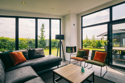 Helles Wohnzimmer mit großen Fenstern und Gartenblick im Holiday Park Zeedijk 3, Niederlande, modern.