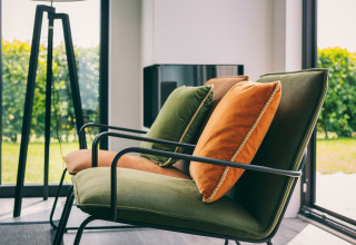Modern lounge chairs with green and orange cushions by large windows at Holiday Park Zeedijk 3, Netherlands.