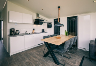 Modern holiday lodge kitchen and dining area at Holiday Park «Zeedijk 3» in the Netherlands, stylishly furnished.