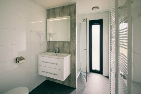 Baño moderno en Holiday Park Zeedijk 3, Países Bajos, con ducha, lavabo, espejo y ventana alta.