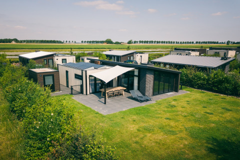 Modern lodges at Holiday Park Zeedijk 3 in the Netherlands, featuring spacious patios and green lawns.