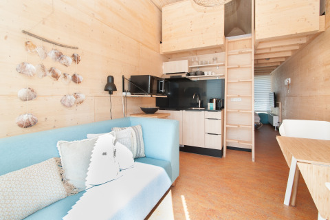 Intérieur lumineux et moderne d'une tiny house à Eco Resort Grevelingenstrand, Pays-Bas, avec mezzanine.