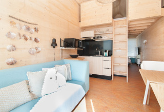 Intérieur lumineux et moderne d'une tiny house à Eco Resort Grevelingenstrand, Pays-Bas, avec mezzanine.