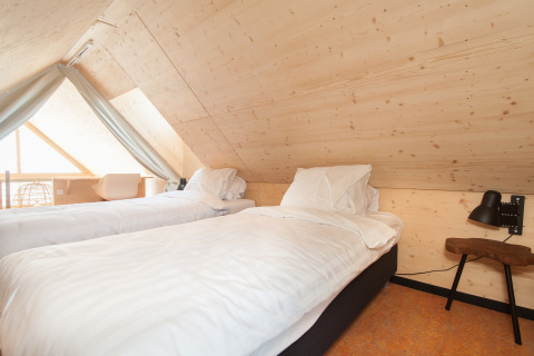 Chambre avec deux lits simples et intérieur en bois dans une tiny house à Eco Resort Grevelingenstrand, Pays-Bas.
