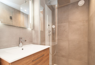 Salle de bain moderne avec douche et meuble en bois d'une tiny house à l'Eco Resort Grevelingenstrand, Pays-Bas.