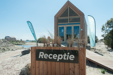 Tiny house en bois avec panneau 'Receptie' à l'Eco Resort Grevelingenstrand, aux Pays-Bas, près de la plage.
