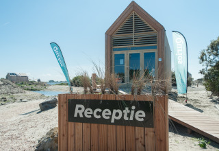 Tiny house en bois avec panneau 'Receptie' à l'Eco Resort Grevelingenstrand, aux Pays-Bas, près de la plage.
