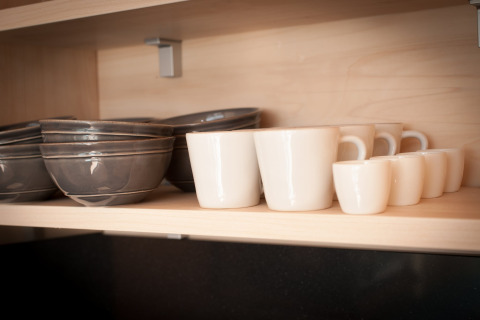 Bols et tasses bien rangés sur une étagère en bois dans une tiny house à l’Eco Resort Grevelingenstrand, Pays-Bas.