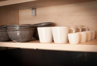 Bols et tasses bien rangés sur une étagère en bois dans une tiny house à l’Eco Resort Grevelingenstrand, Pays-Bas.