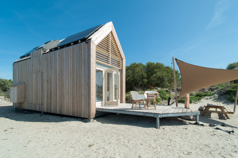 Tiny house moderne à l’Eco Resort Grevelingenstrand aux Pays-Bas, avec terrasse en bois et auvent.