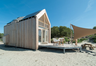 Tiny house moderne à l’Eco Resort Grevelingenstrand aux Pays-Bas, avec terrasse en bois et auvent.