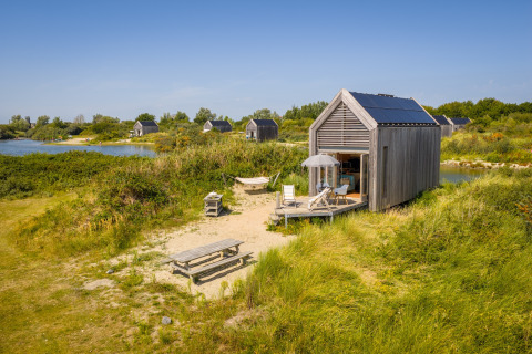 Petite maison en bois avec panneaux solaires à l’Eco Resort Grevelingenstrand aux Pays-Bas, près d’un lac.