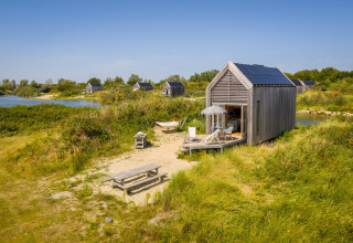 Petite maison en bois avec panneaux solaires à l’Eco Resort Grevelingenstrand aux Pays-Bas, près d’un lac.