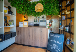 Accueil de l’Eco Resort Grevelingenstrand aux Pays-Bas, avec plantes vertes et panneau de bienvenue.