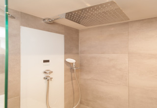 Douche moderne avec grand pommeau pluie et douchette à main dans un tiny house à Eco Resort Grevelingenstrand.