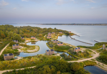 Luftfoto af tiny houses ved søbred i Eco Resort Grevelingenstrand, omgivet af natur i Holland.