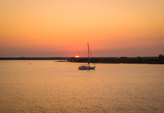 Magnifique coucher de soleil sur l’eau à l’Eco Resort Grevelingenstrand, aux Pays-Bas, avec un voilier.