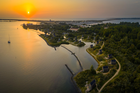 Coucher de soleil à l’Eco Resort Grevelingenstrand avec des petites maisons au bord de la côte néerlandaise