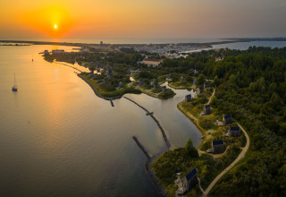 Coucher de soleil à l’Eco Resort Grevelingenstrand avec des petites maisons au bord de la côte néerlandaise