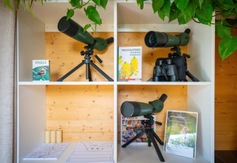 Kikkert og naturbøger på en hvid reol i et tiny house på Eco Resort Grevelingenstrand, Holland.