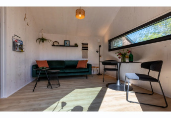 Salon lumineux et moderne dans le Tinyhouse «La Mouette» aux Pays-Bas, avec canapé et table à manger.