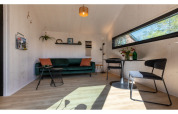 Salon lumineux et moderne dans le Tinyhouse «La Mouette» aux Pays-Bas, avec canapé et table à manger.