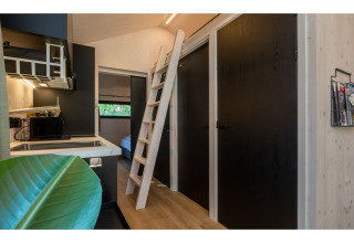 Interieur van Tinyhouse «La Mouette» in Nederland, met keukentje, ladder naar mezzanine en zwarte deuren.