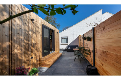 Moderne terras bij Tinyhouse «La Mouette» in Nederland met houten wanden en gezellige zithoek.