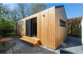 Tiny house moderne «La Mouette» aux Pays-Bas avec façade en bois, terrasse extérieure et nature environnante.