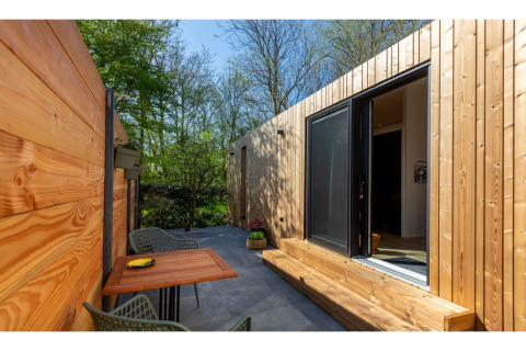 Buitenterras bij Tinyhouse «La Mouette» in Nederland, met houten wanden en moderne zitplaatsen.