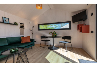 Licht interieur van Tinyhouse «La Mouette» in Nederland met groene zetel en eettafel.