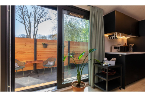 Uitzicht vanuit Tinyhouse 'La Mouette' op terras met houten schutting en stoelen in Nederland.