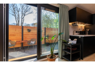 Uitzicht vanuit Tinyhouse 'La Mouette' op terras met houten schutting en stoelen in Nederland.