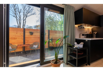 Vue intérieure du Tinyhouse «La Mouette» vers terrasse agréable, clôture bois et chaises, aux Pays-Bas.