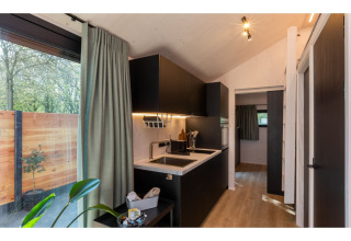 Moderne kitchenette in Tinyhouse ‘La Mouette’ met grote ramen en terraszicht in Nederland.